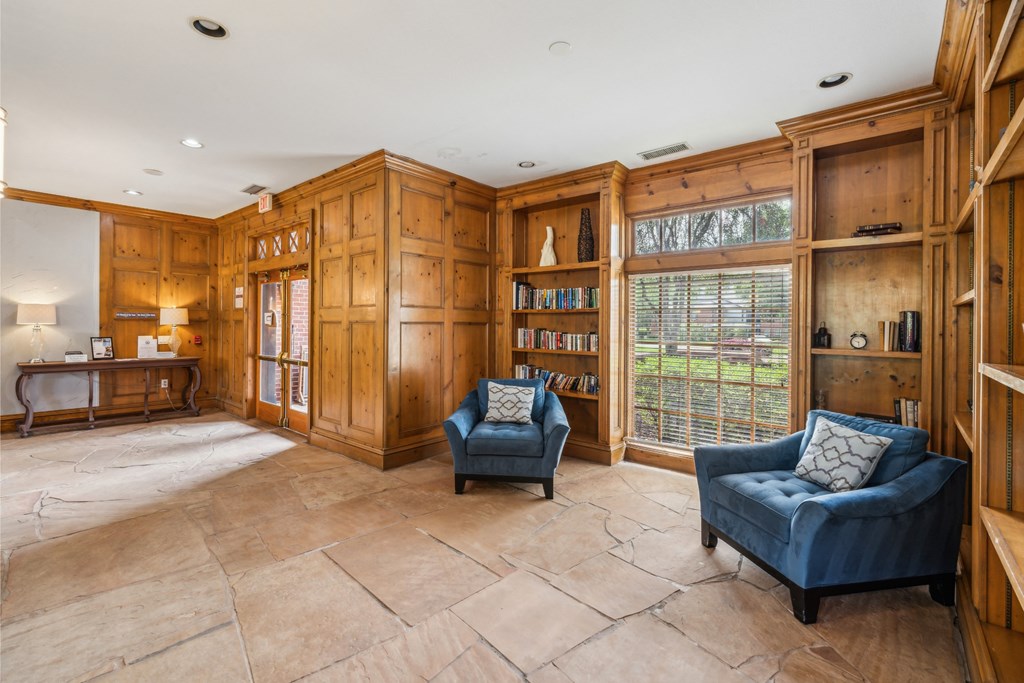 a library with two blue chairs and wooden bookcases