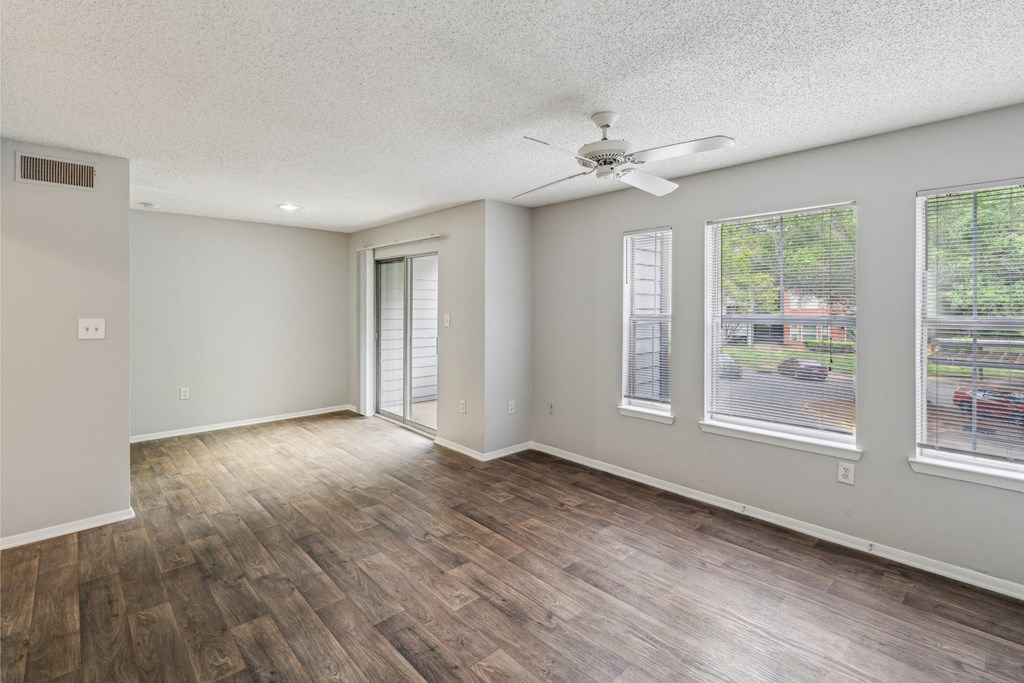 an empty living room with a ceiling fan and windows
