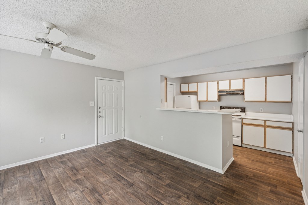 an empty living room and kitchen with a ceiling fan