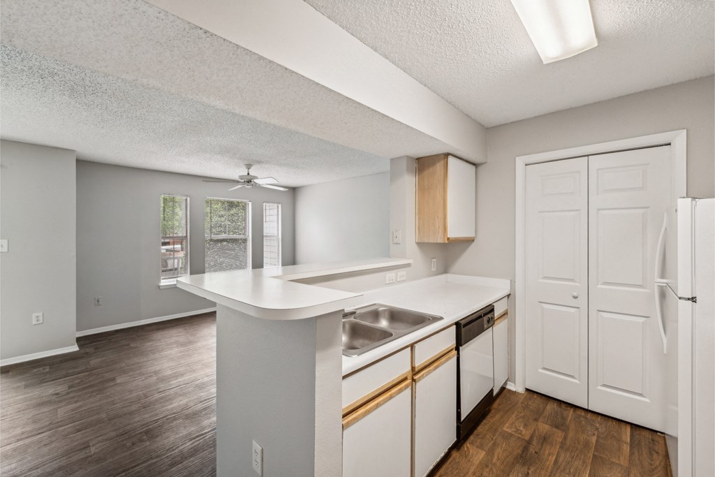 an empty kitchen with white cabinets and a stainless steel sink