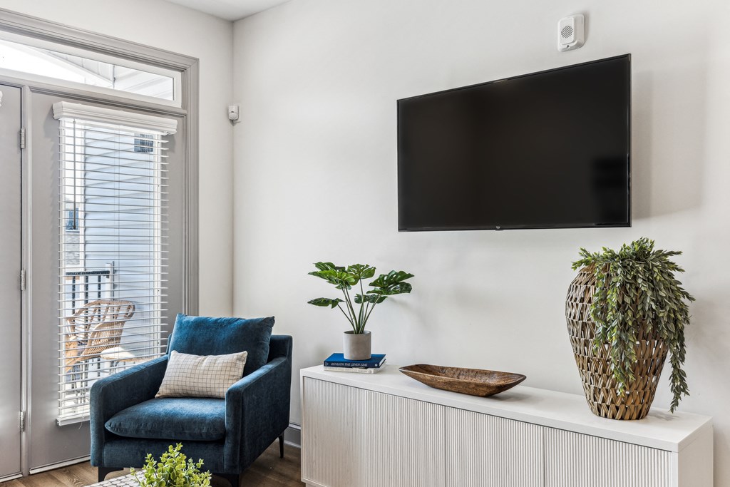 a living room with a blue chair and a tv on the wall