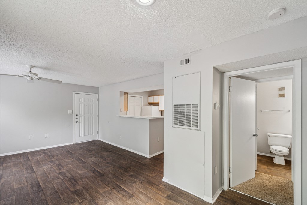 an empty living room and bathroom with a toilet and a closet