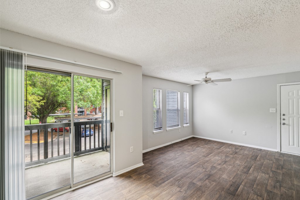 an empty living room with a sliding glass door to a balcony