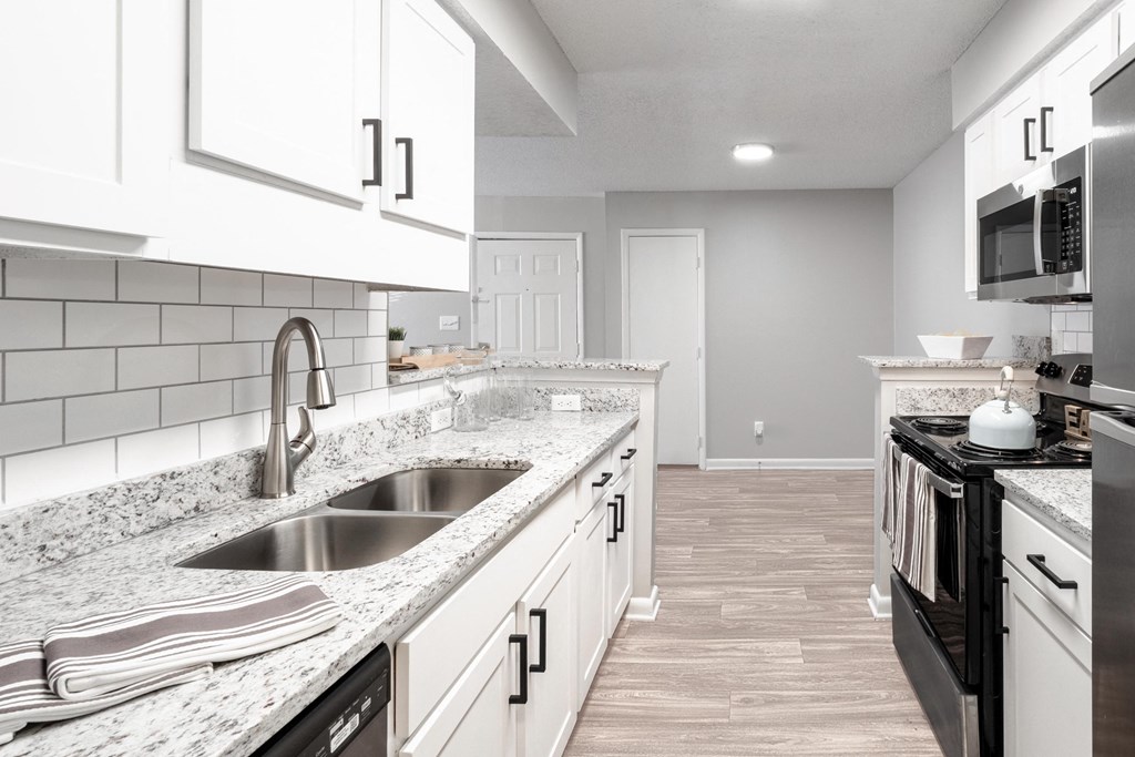 a kitchen with white cabinets and granite counter tops and a sink