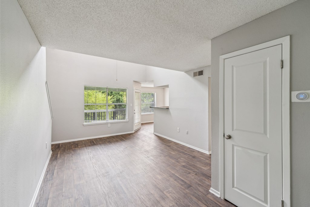 the living room of an apartment with white walls and wood flooring