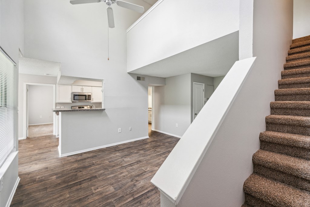 a living room and staircase with a kitchen in a house