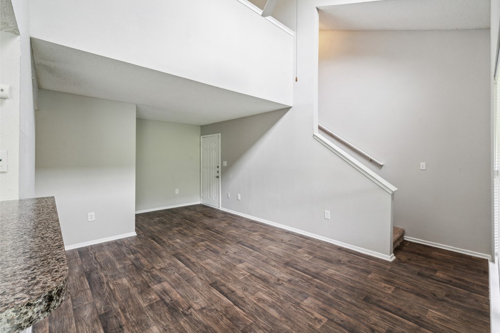 an empty living room with wood flooring and white walls