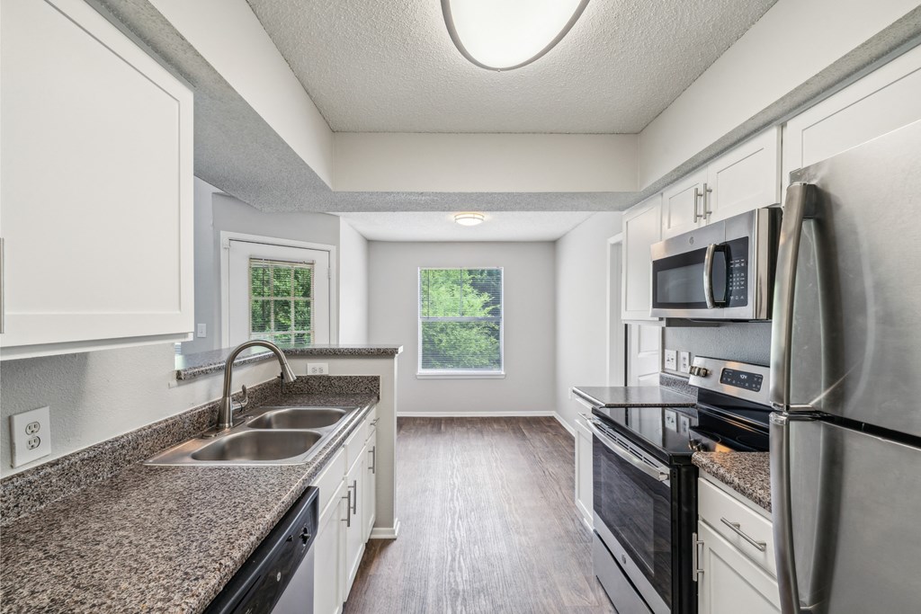 an empty kitchen with granite counter tops and white cabinets