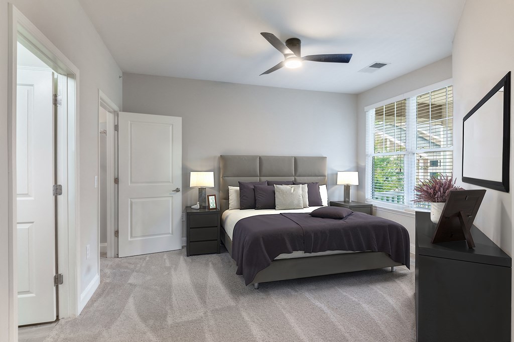 A bedroom with a bed, nightstands, and a ceiling fan.
