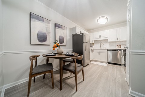 A kitchen with a table and chairs in the foreground and a refrigerator in the background.