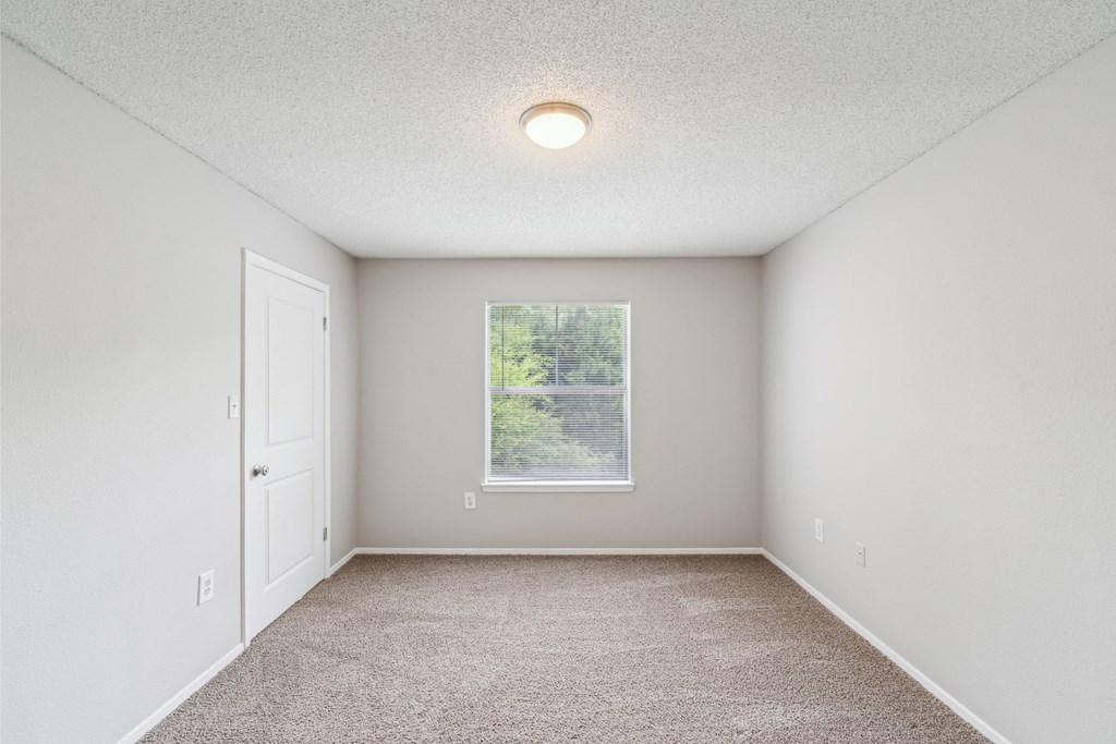 an empty room with carpet and a window