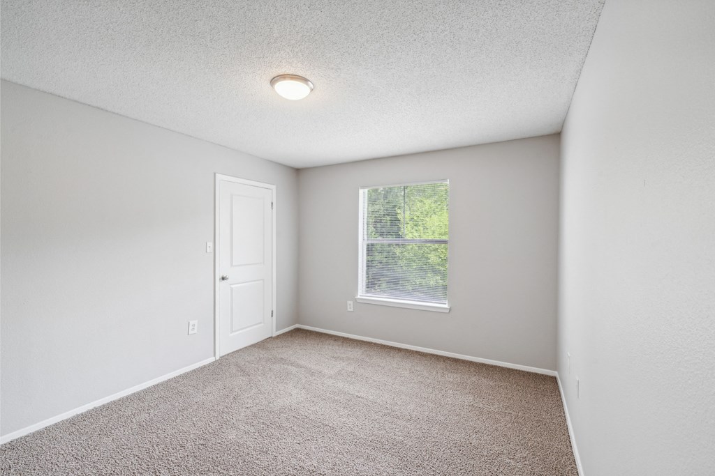 an empty room with carpet and a window