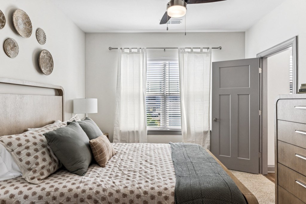 a bedroom with a bed and a window with white curtains
