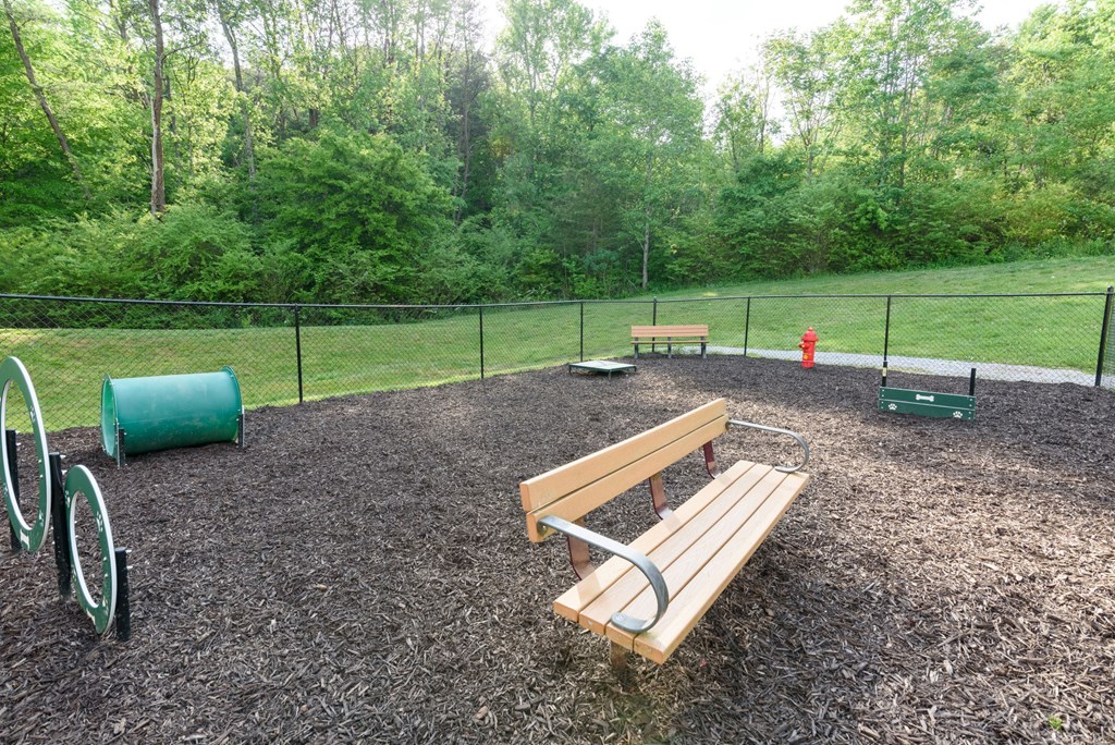 A playground with a wooden slide and a green barrel.