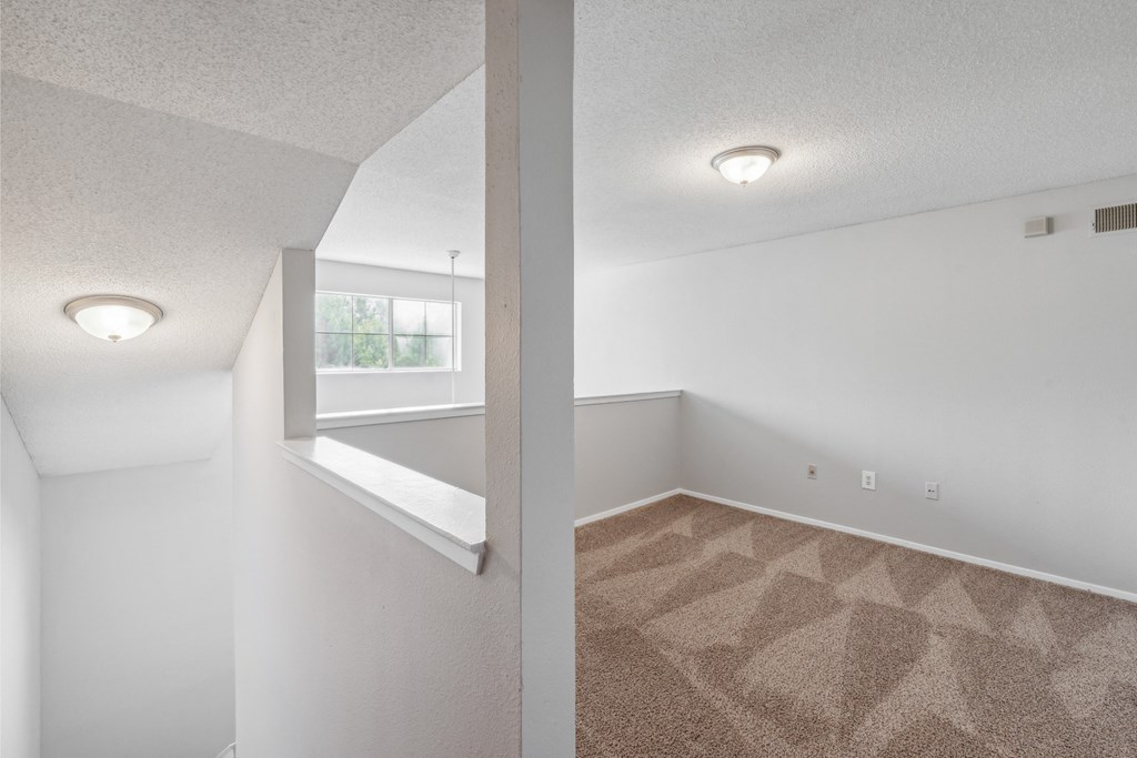 the living room and dining room of an apartment with carpet and a window