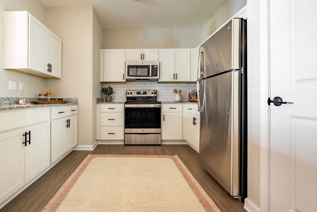 an open kitchen with stainless steel appliances and white cabinets