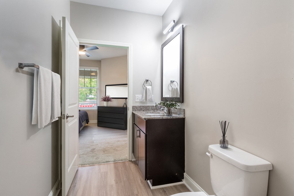 A bathroom with a toilet, sink, and mirror.