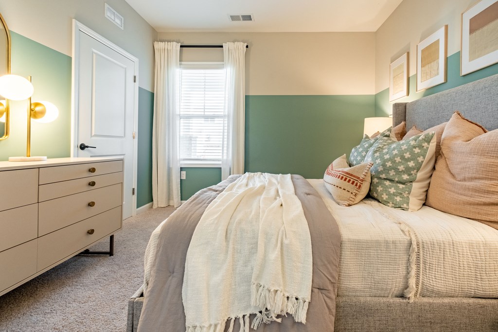 a bedroom with green and white walls and a bed with pillows
