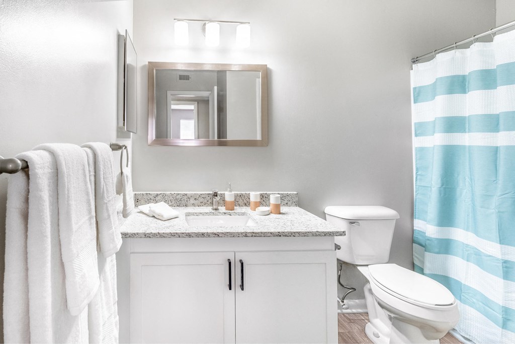 a white bathroom with a blue and white shower curtain