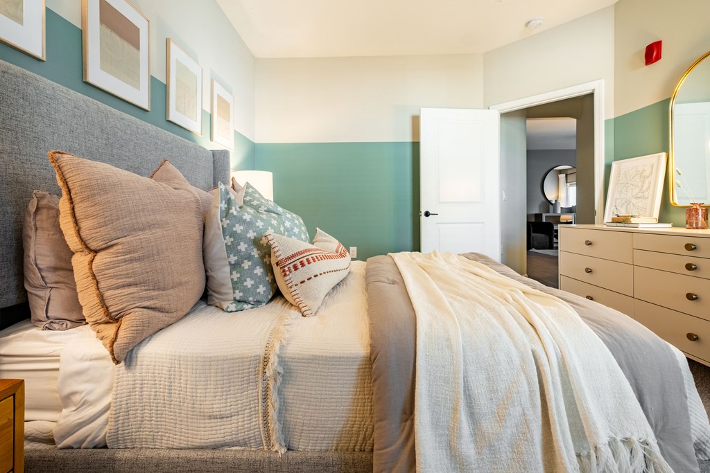 a bedroom with a bed with pillows and a dresser