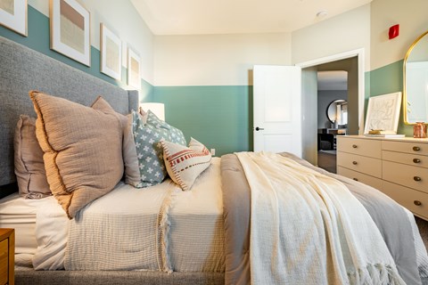 a bedroom with a bed with pillows and a dresser