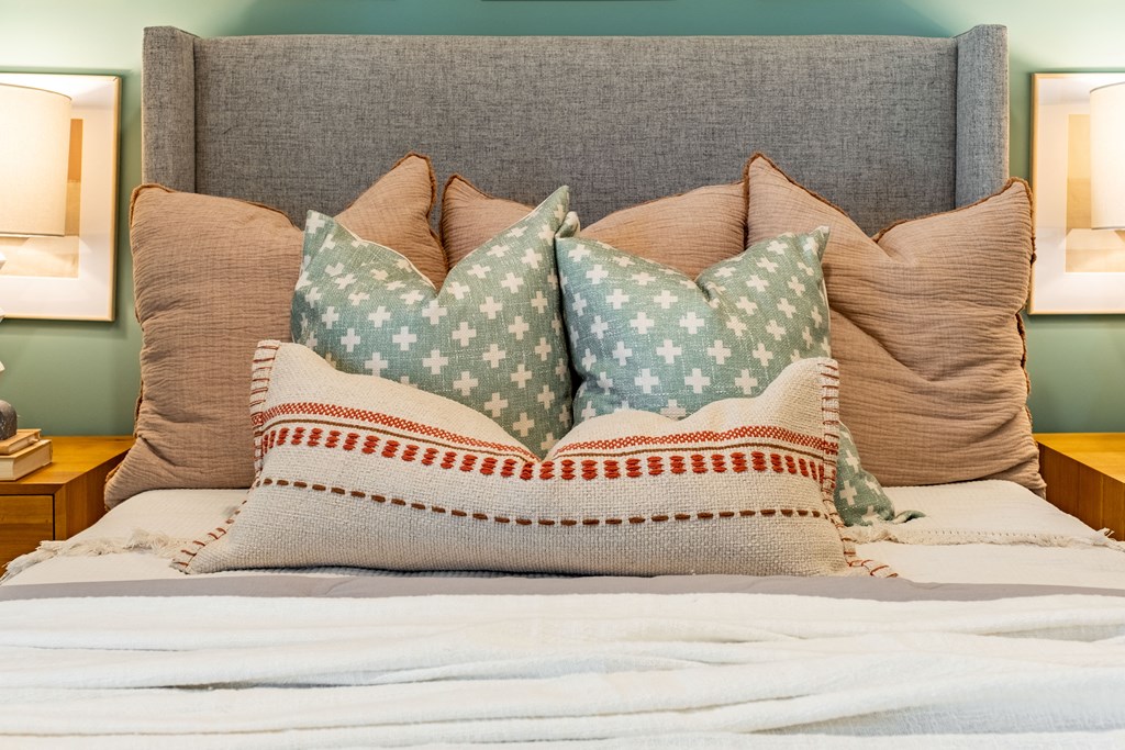 a bed with pillows on it and a grey headboard