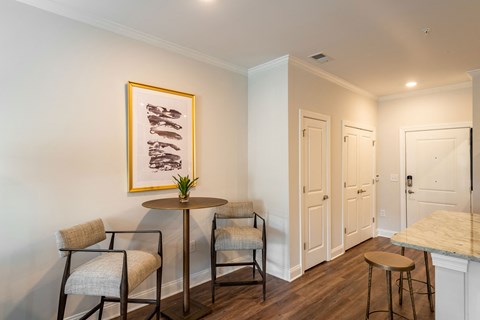 a living room with a table and chairs and a hallway with two doors