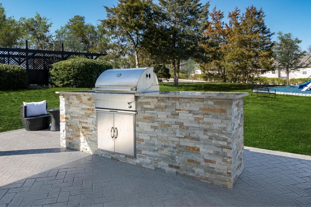 a barbecue grill in the middle of a stone patio