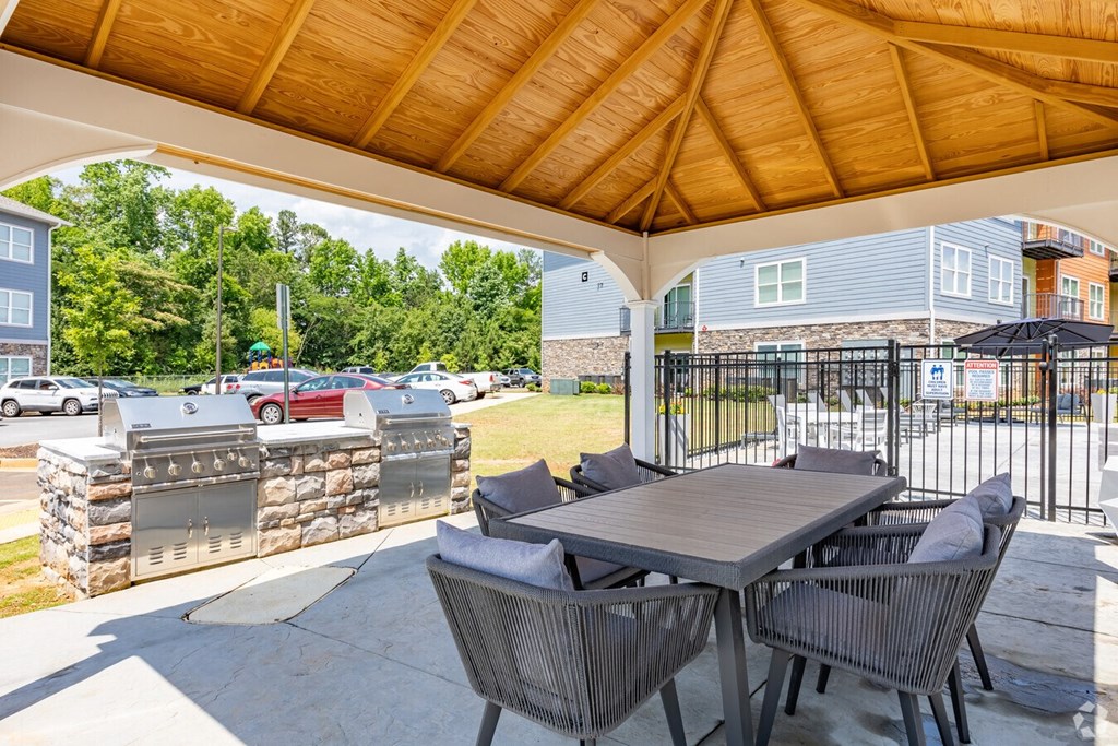 a patio with a table and chairs and a grill