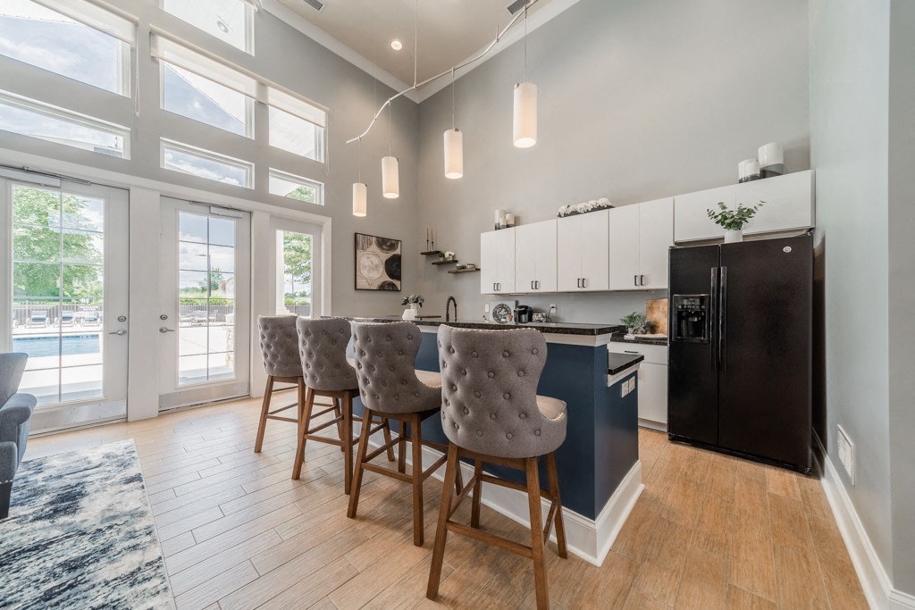 Clubhouse kitchen with a black refrigerator and a dining table with chairs.