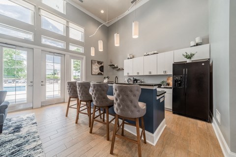 A kitchen with a black refrigerator and a dining table with chairs.