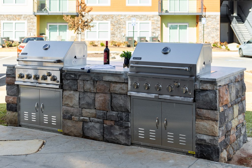 two stainless steel barbecue grills in front of a building