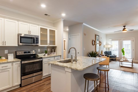 an open kitchen and living room with a marble counter top