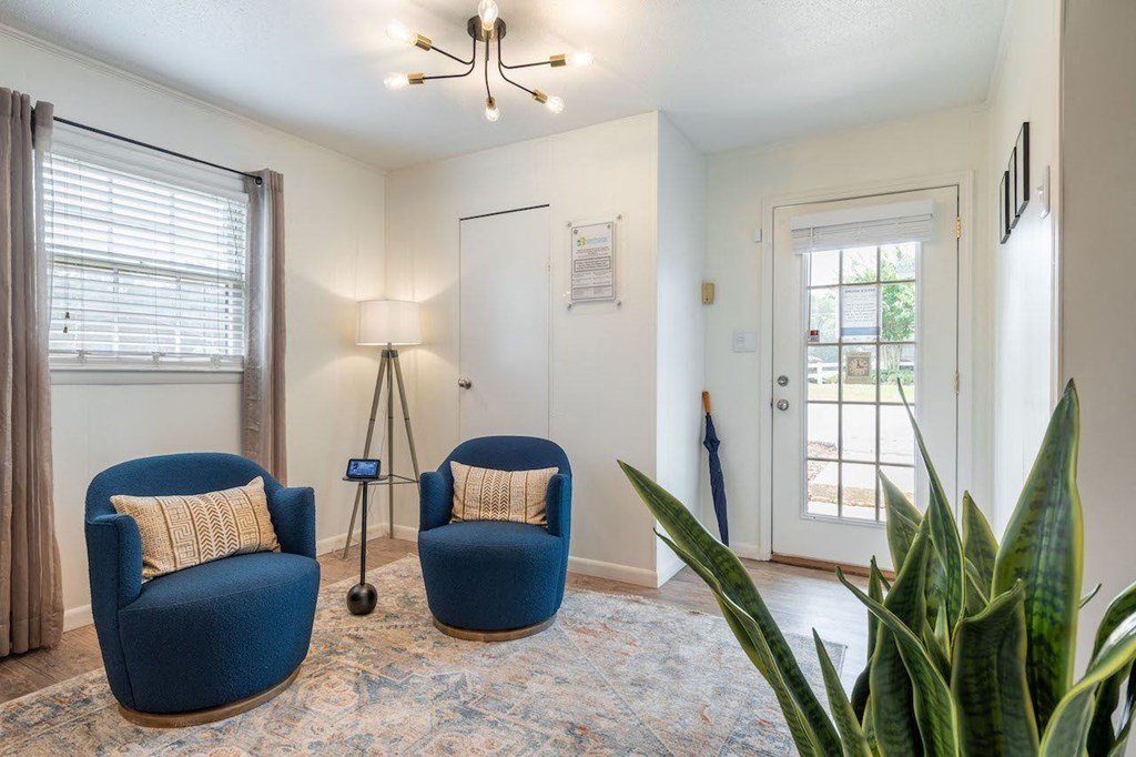 a living room with two blue chairs and a plant