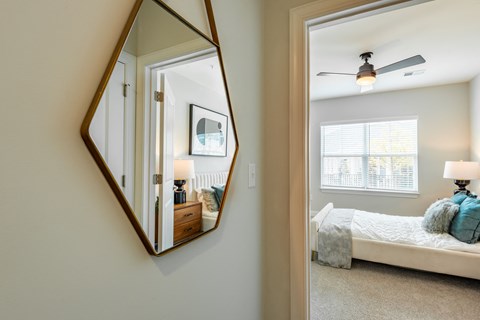a mirror hanging on a wall next to a bedroom with a bed