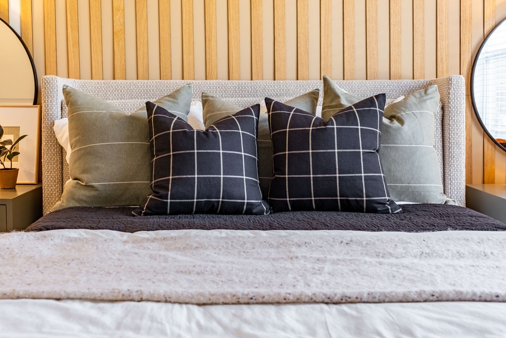 a bed with pillows in front of a wooden wall