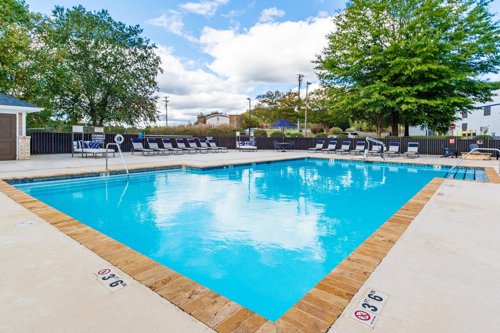 A large swimming pool with a blue water surface and a wooden edge.