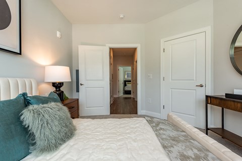 a bedroom with a large white bed and a mirror