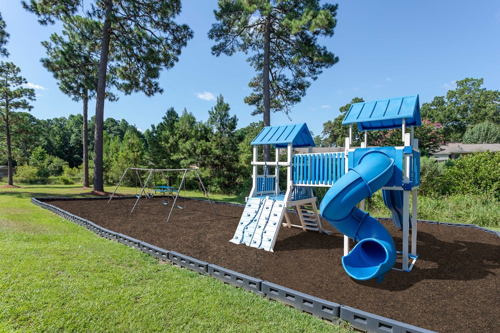 a playground with a blue slide and a swing set
