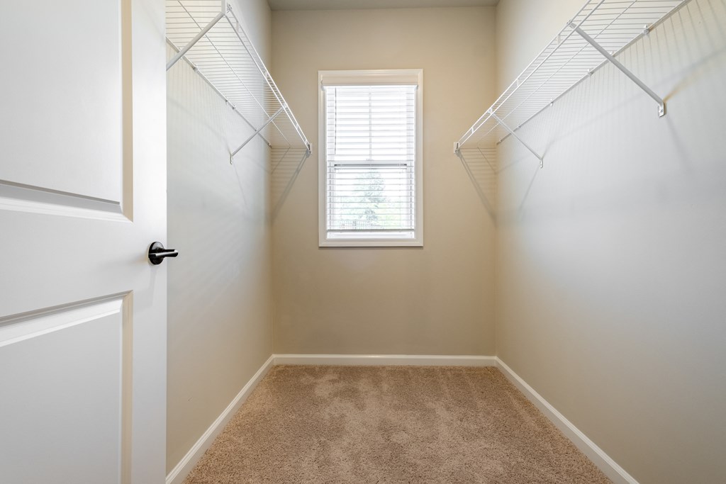an empty closet with two hanging racks and a window