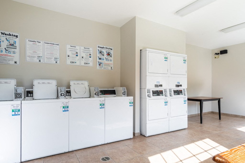 a laundry room with several washers and dryers and a table with washing machines