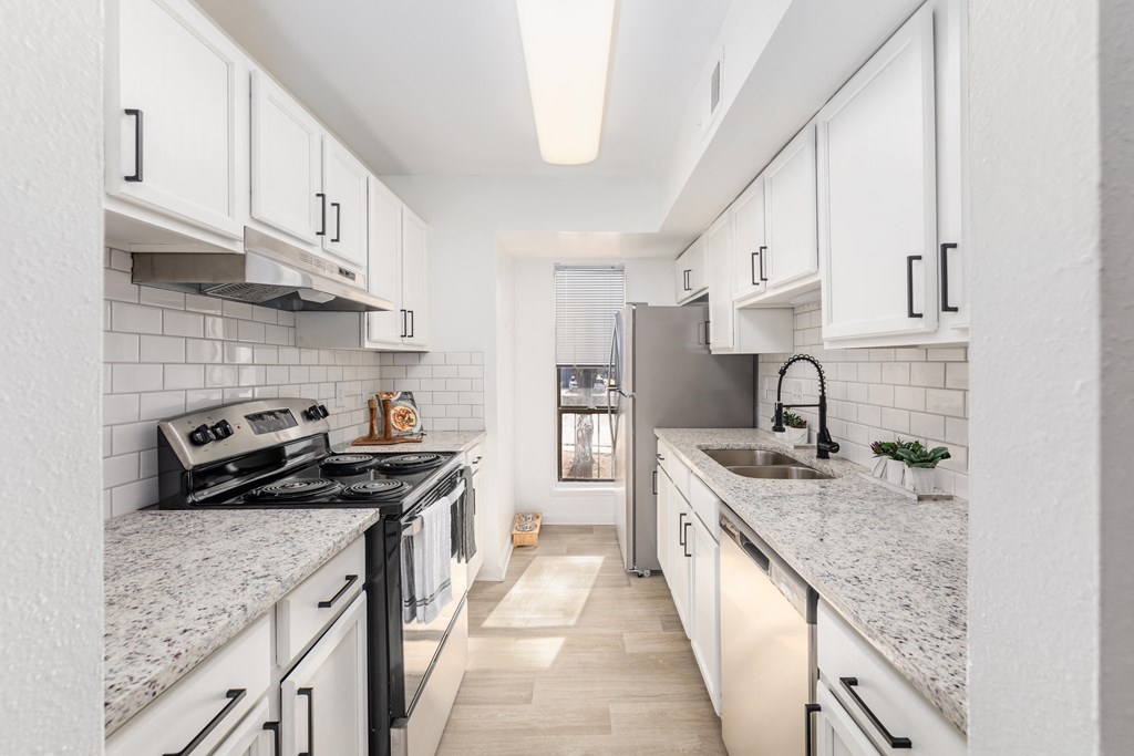 a kitchen with marble counter tops and white cabinets