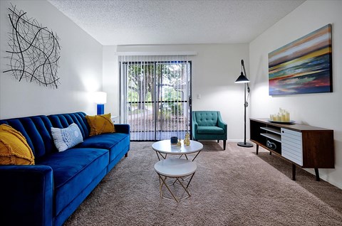 A living room with a blue couch, a green chair, a coffee table, and a painting on the wall.