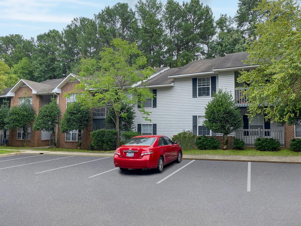 a red car parked in a parking lot in front of a house