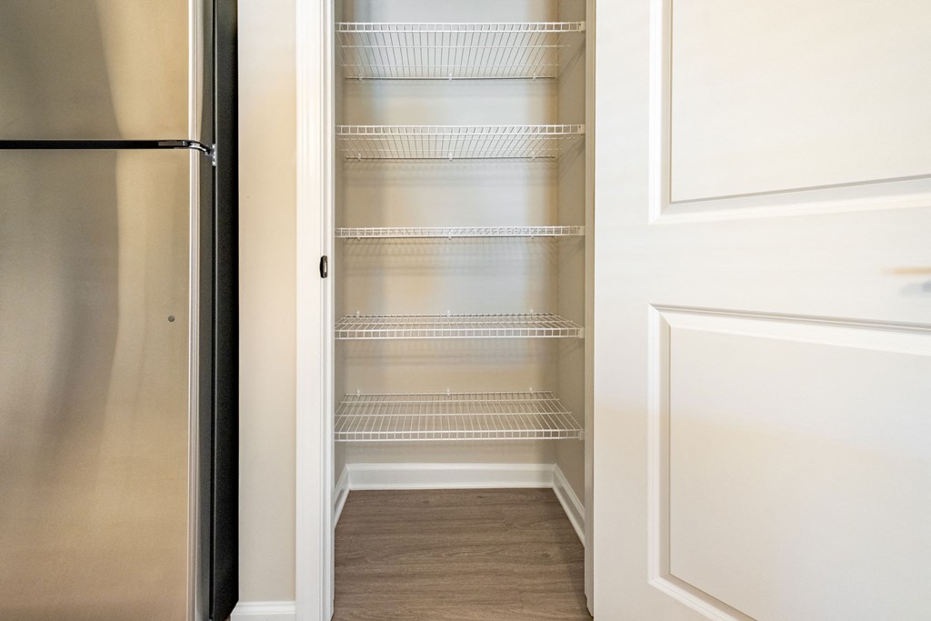 the closet in the master bedroom of a home with a stainless steel refrigerator