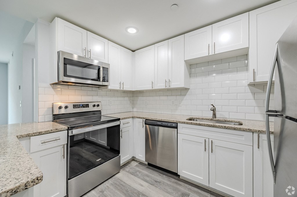an empty kitchen with white cabinets and stainless steel appliances