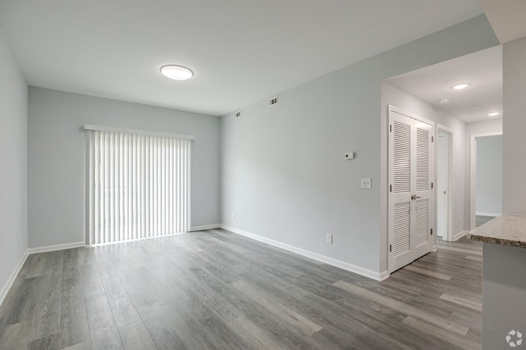 an empty living room with a large window and wood flooring