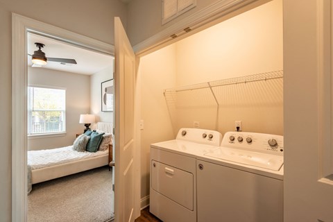 a washer and dryer in a room next to a bedroom with a bed