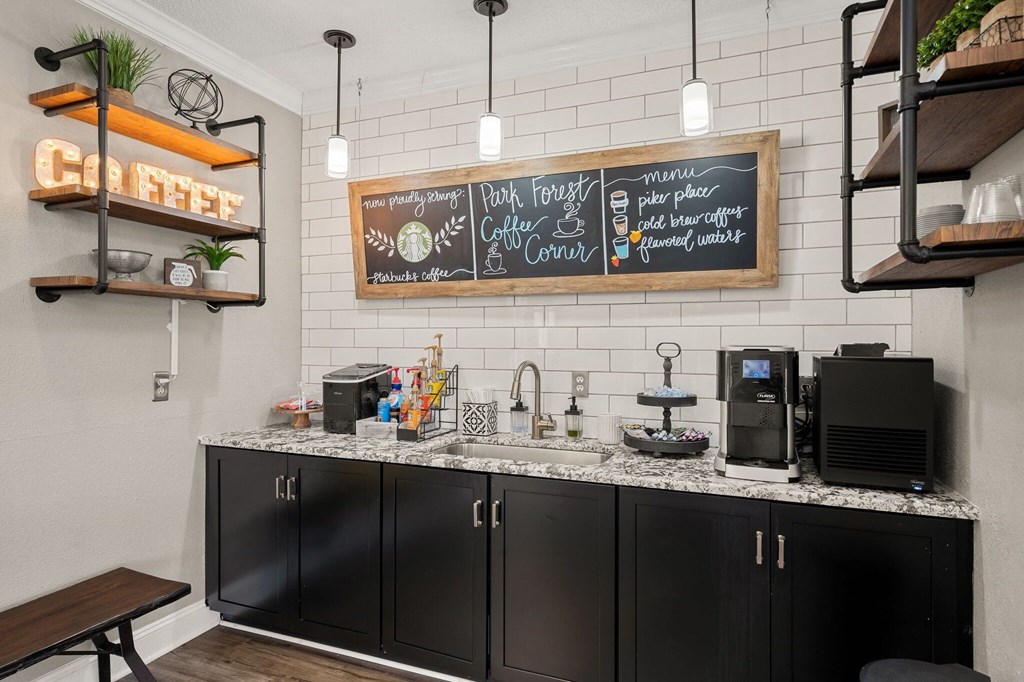 a kitchen with black cabinets and a counter top with a sink and a coffee bar