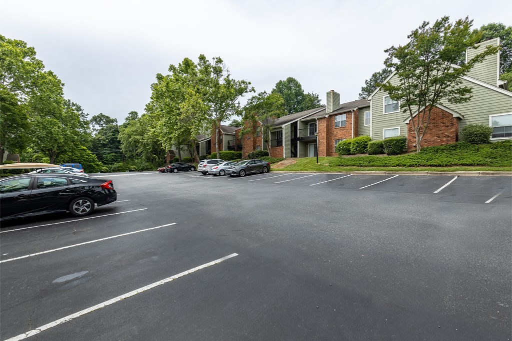 an empty parking lot in front of apartment buildings with cars parked on the street